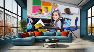 Disabled school girl on wheelchair holding a book in classroom Wall mural