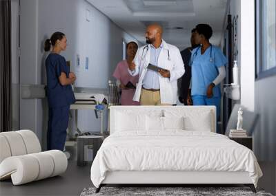 Diverse doctors discussing work and walking through corridor at hospital Wall mural