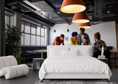 Diverse male and female colleagues in discussion using laptop and tablet in casual office meeting Wall mural