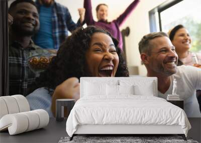 Excited diverse male and female friends watching sport on tv at home and drinking beers, copy space Wall mural