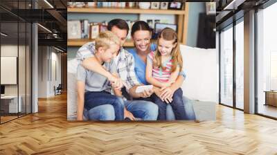 Family using mobile phone while sitting on sofa Wall mural