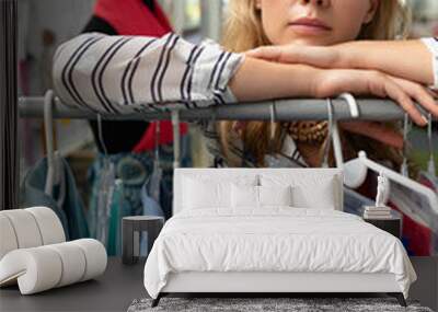 Female fashion designer leaning on clothes rack in design studio Wall mural