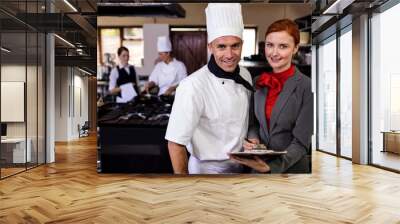 Female manager and male chef writing on clipboard in kitchen Wall mural