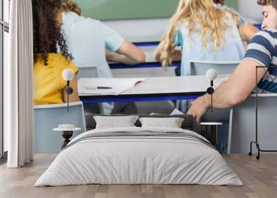 Female student passing note to friend in classroom Wall mural