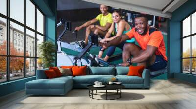 Fit people exercising with rowing machine in fitness center Wall mural