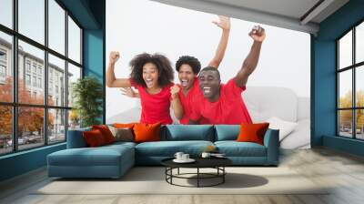 Football fans sitting on couch cheering together Wall mural