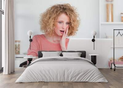 Good looking blonde female relaxing with her laptop while sittin Wall mural