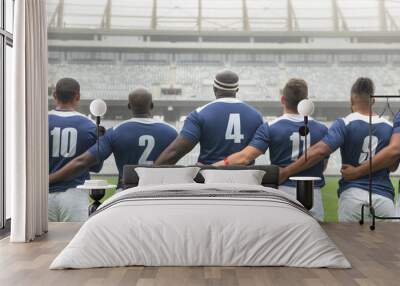 Group of diverse male rugby players taking pledge together in stadium Wall mural