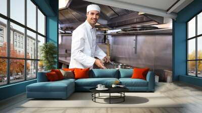 Handsome chef looking at pans Wall mural