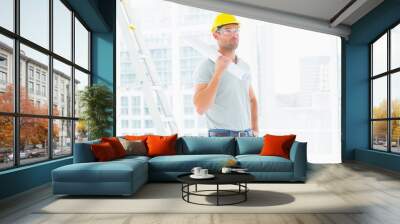 Handyman holding rolled up blueprint in bright office Wall mural