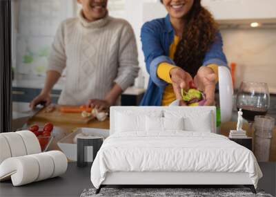 Happy biracial couple preparing food and composting vegetable waste in kitchen Wall mural