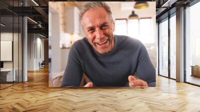 Happy caucasian man sitting on sofa in living room and having video call Wall mural