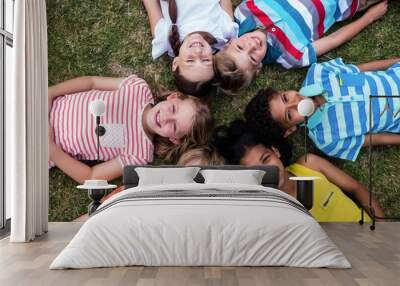 Happy children lying on grass Wall mural