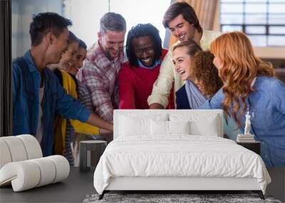 Happy colleagues piling up their hands Wall mural