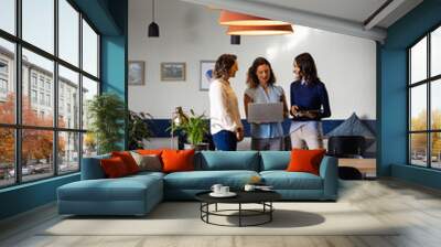 Happy diverse casual businesswomen discussing using laptop and tablet in office Wall mural