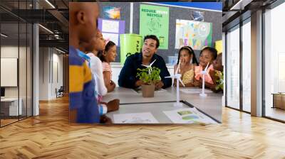 Happy diverse male teacher and children in elementary school class with windmills and plants Wall mural