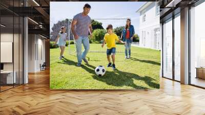 Happy family playing football in the park Wall mural