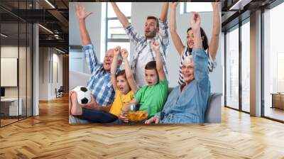 Happy family watching a football match at home Wall mural