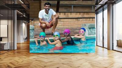 Happy male trainer with little swimmers at poolside Wall mural