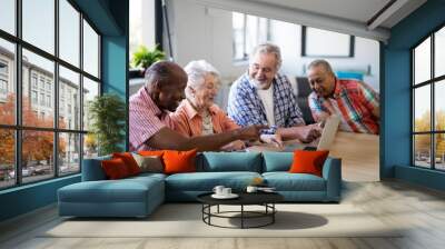 Happy mixed race senior men and woman using laptop Wall mural