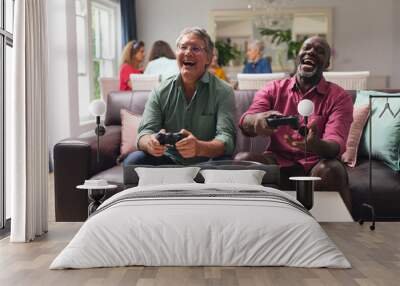 Happy multiracial senior male friends playing video game at home Wall mural