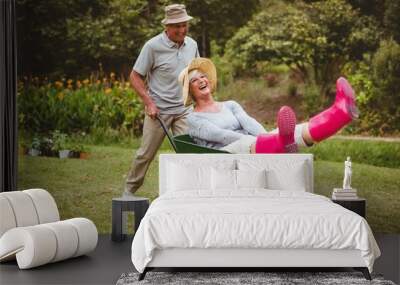 Happy senior couple playing with a wheelbarrow  Wall mural