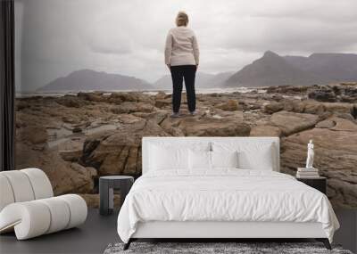 Happy senior woman standing on the rock at beach Wall mural