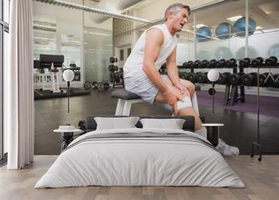 Injured man gripping his knee in the weights room Wall mural