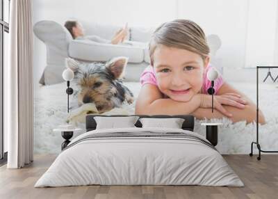 Little girl lying on rug with yorkshire terrier smiling at Wall mural