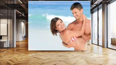 Man carrying his wife at the beach Wall mural