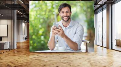 Man smiling while using his mobile phone n the restaurant Wall mural