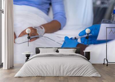 Midsection of african american male doctor giving iv injection to female patient in hospital bed Wall mural