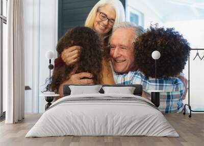 Multiracial grandchildren embracing cheerful grandparents and welcoming them at home at entrance Wall mural