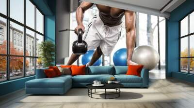 Muscular man doing push up with kettlebells Wall mural