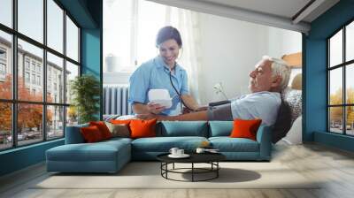 Nurse checking blood pressure of senior man Wall mural