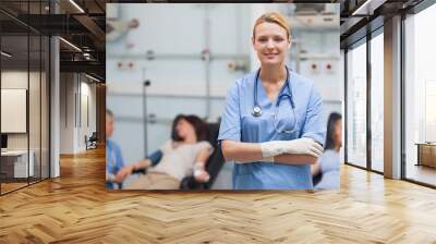 Nurse standing with arms crossed next to patients Wall mural