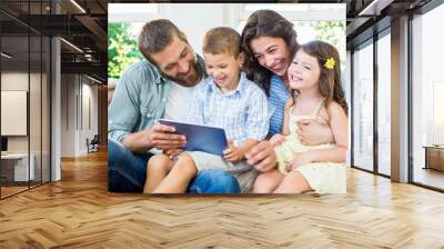 Parents and kids using digital tablet in living room Wall mural