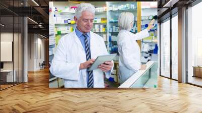 Pharmacist using digital tablet and co-worker checking medicines Wall mural