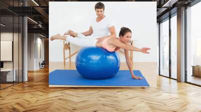 Physical therapist assisting young woman with yoga ball Wall mural