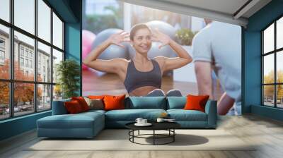 Physiotherapist assisting a female patient while exercising Wall mural