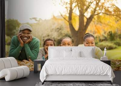 Portrait of a young smiling family lying in leaves Wall mural