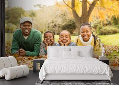 Portrait of a young smiling family lying in leaves Wall mural