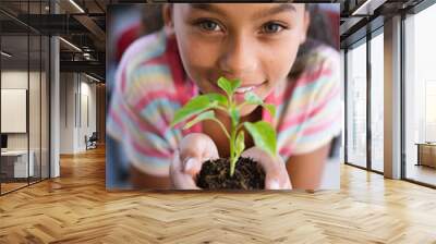 Portrait of african american girl holding a plant seedling in the class at school Wall mural