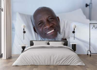 Portrait of african american male patient lying on hospital bed smiling to camera Wall mural