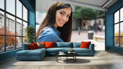 Portrait of beautiful woman sitting on chair at sidewalk cafe Wall mural