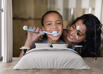 Portrait of girl brushing teeth with mother in bathroom Wall mural