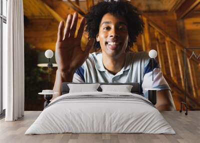 Portrait of happy african american man spending time in log cabin and having video call Wall mural