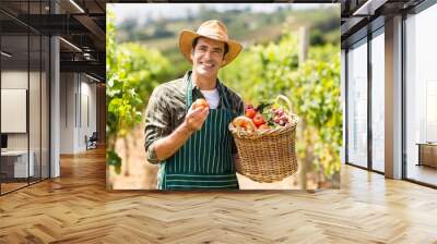 Portrait of happy farmer holding a basket of vegetables Wall mural