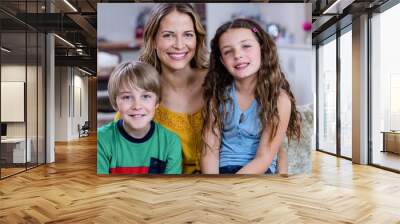 Portrait of happy mother and kids sitting on a sofa Wall mural