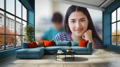 Portrait of happy schoolgirl sitting in classroom Wall mural